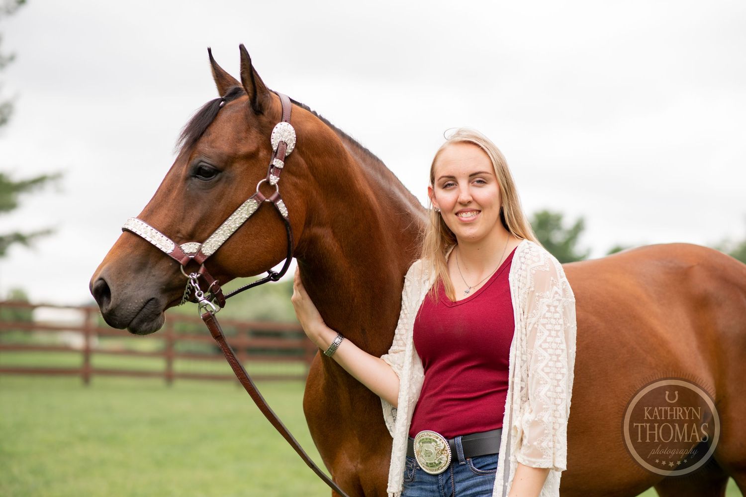 A brown horse with white markings poses with someone in a red top and white cardigan.