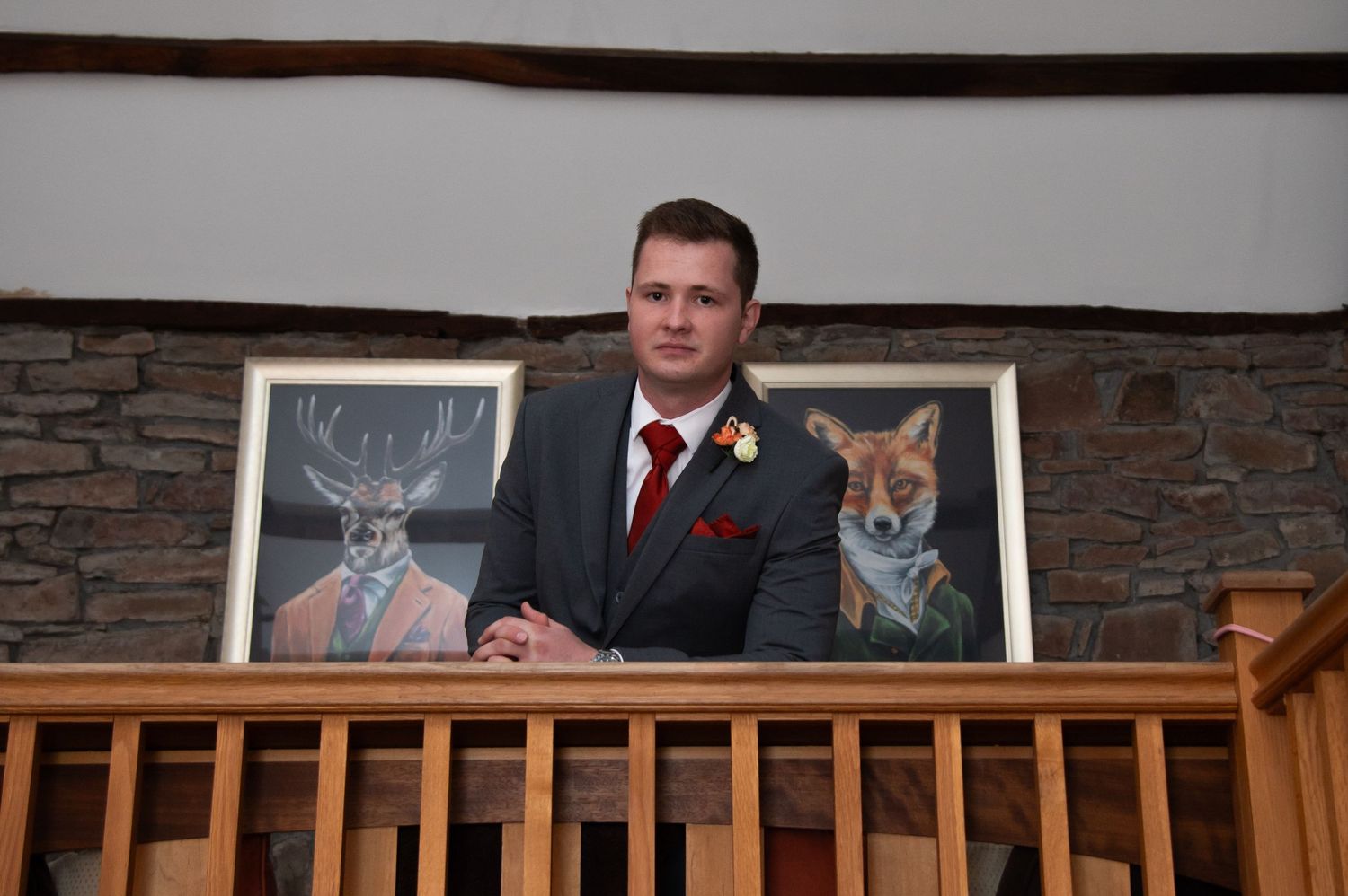 Wedding party members relaxing at a rustic venue with stone walls and wood railing.