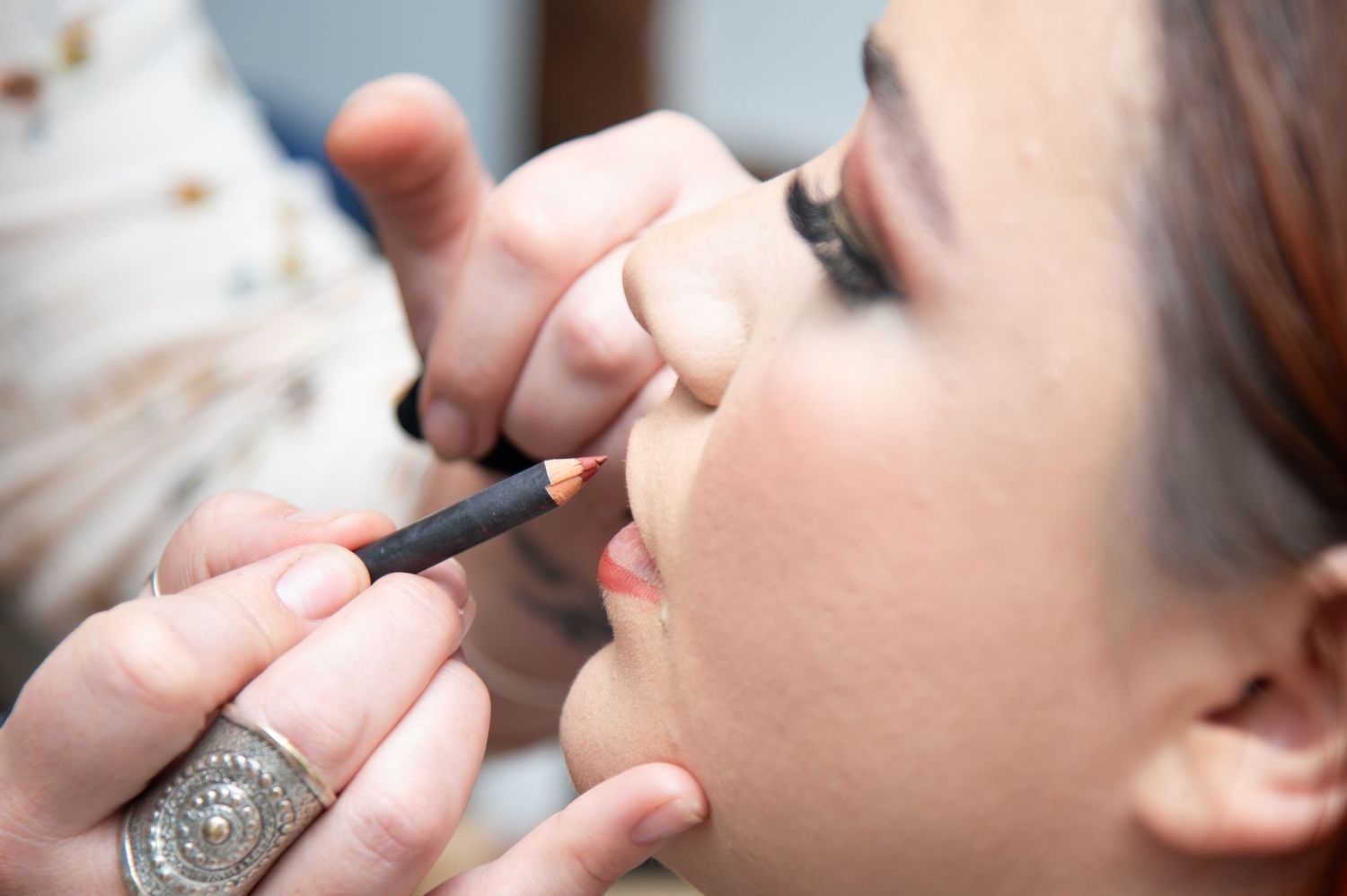 Professional makeup artist applying eye makeup during wedding preparation.