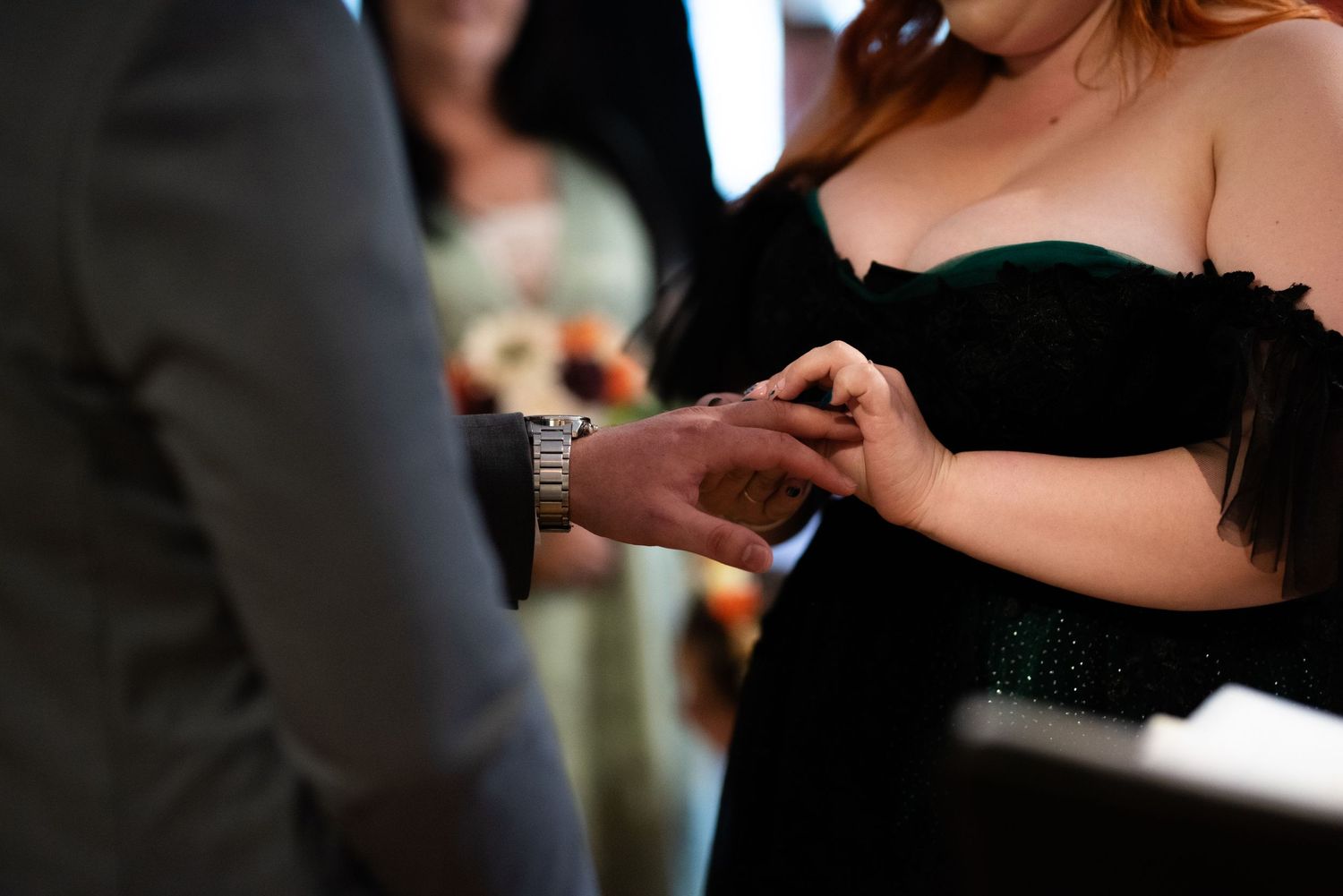Close-up hands exchanging rings during an intimate wedding ceremony moment.