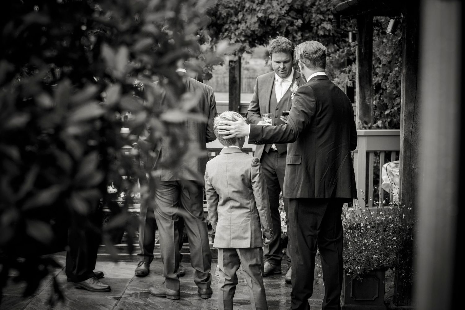 Black and white candid shot of wedding guests interacting outside.