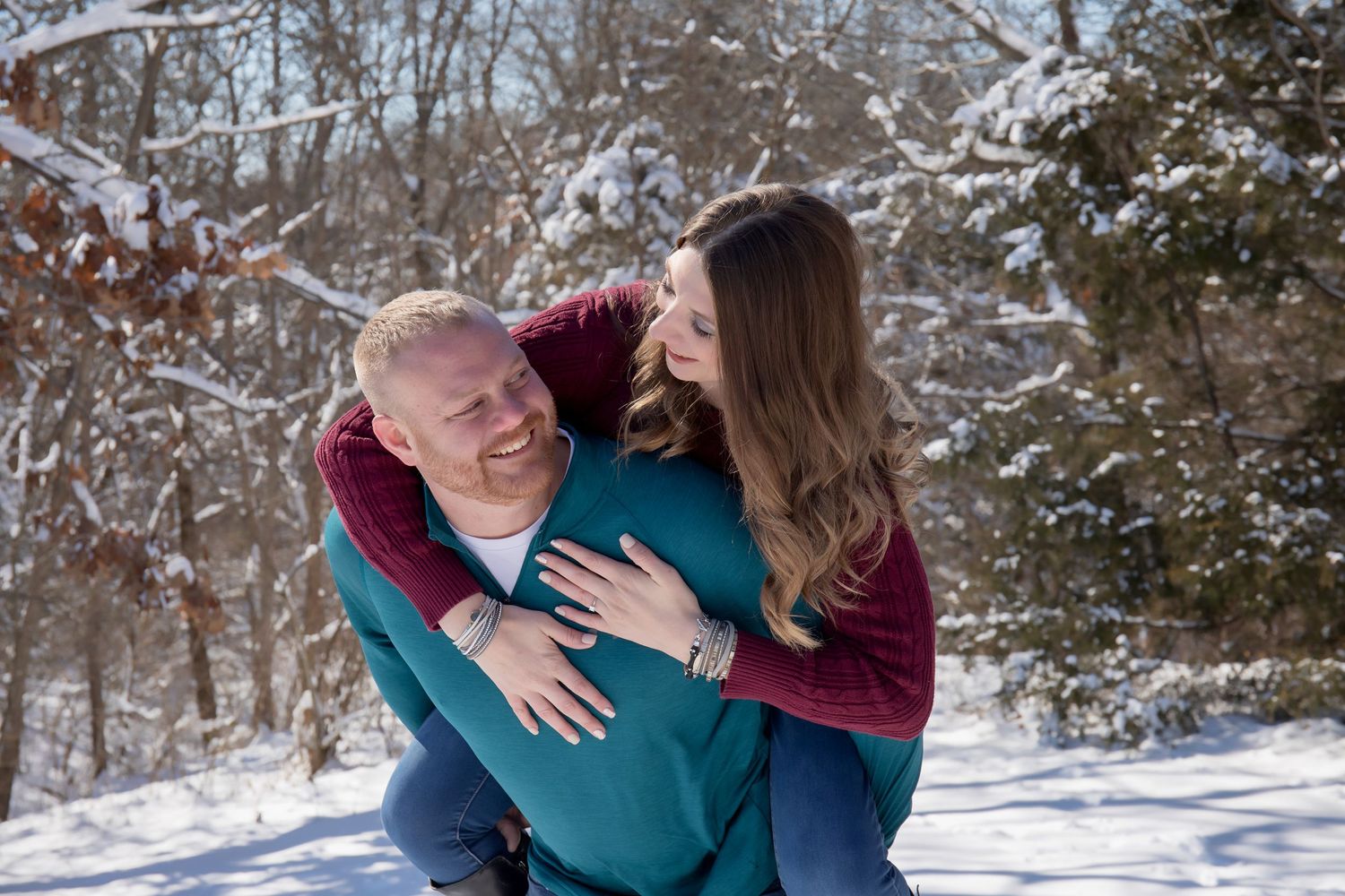 Happy couple playing and laughing together in a snowy winter forest setting.