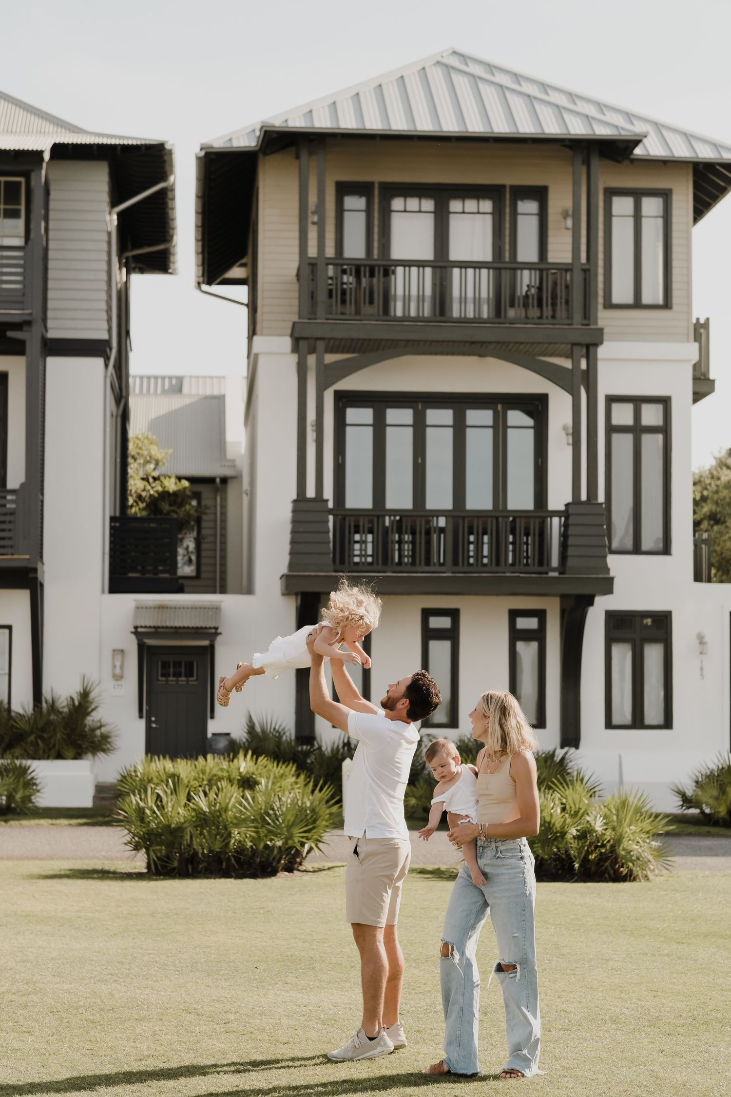 Playful moments captured in front of coastal-style architecture with white exterior.