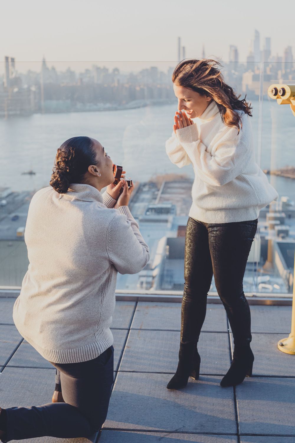 A surprise proposal moment on a rooftop observation deck with city views.