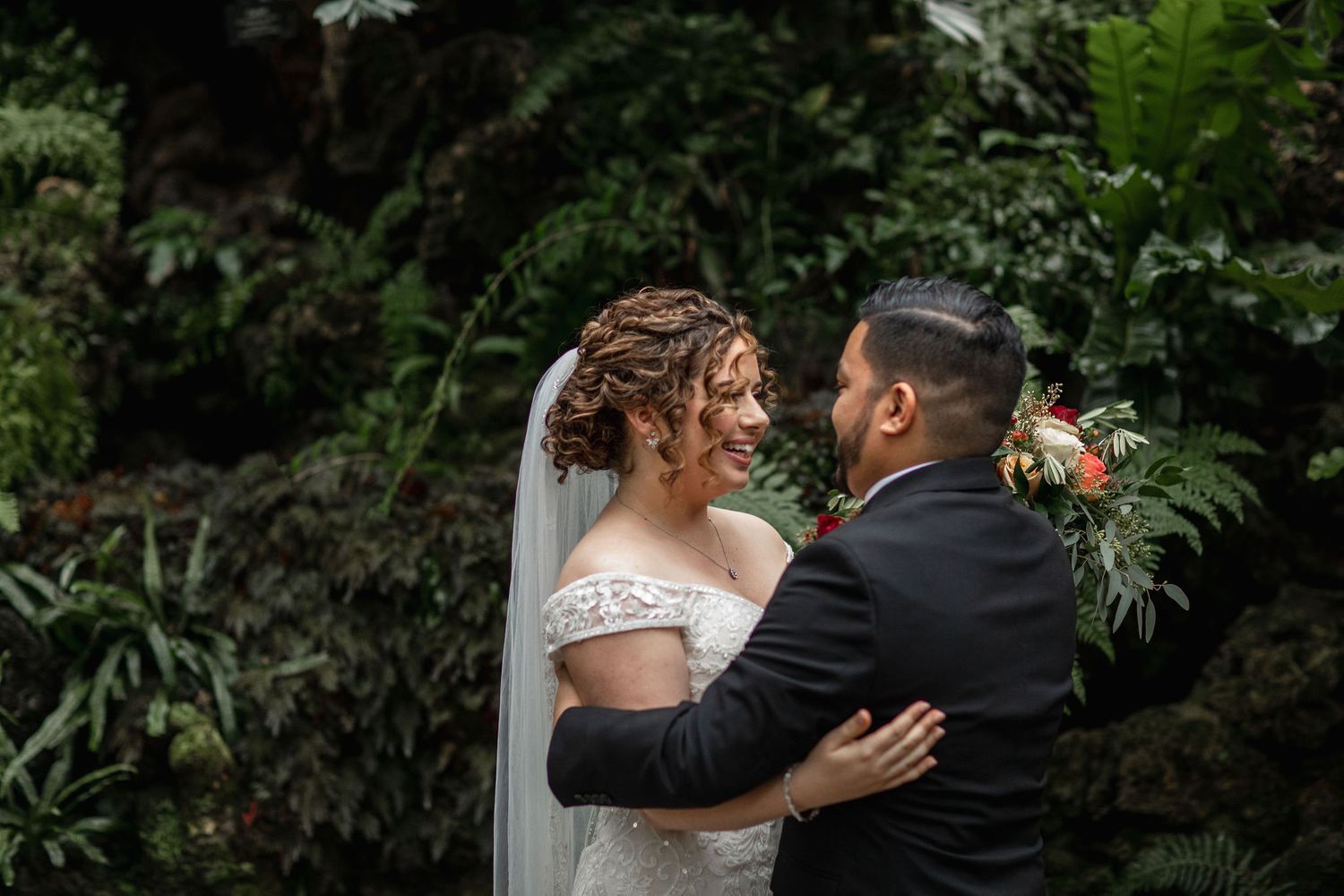A romantic embrace captured in a garden setting with lush greenery.