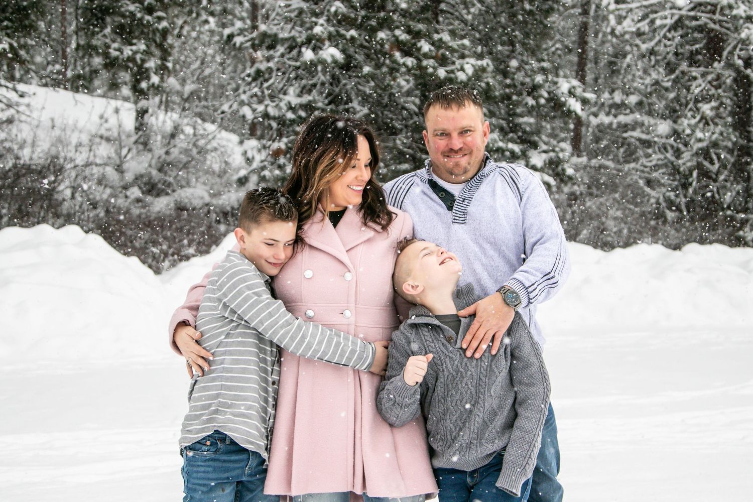 A group embraces while posing for a portrait in the snow-covered woods.