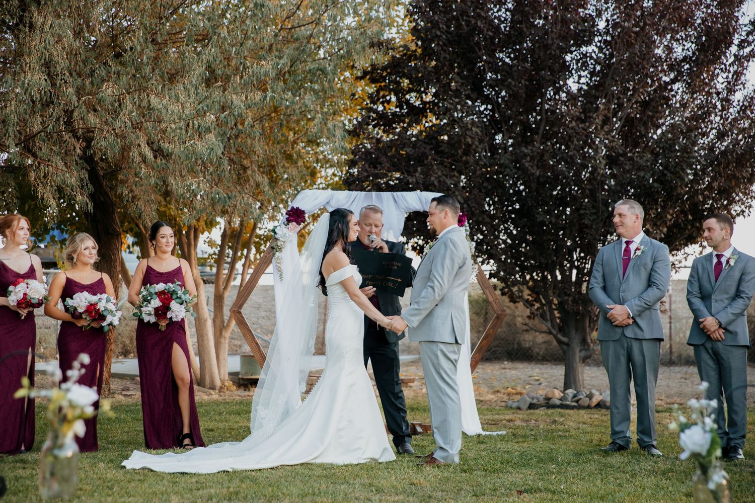Backyard wedding in Fallon, Nevada bride and groom holding hands at the arch wedding day portrait