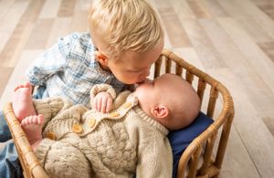 Child resting on wooden floor next to woven basket.