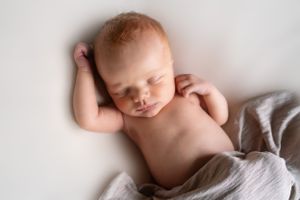 Overhead view of sleeping newborn on white blanket.