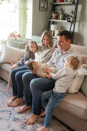 Family sharing joyful moment together on living room sofa surrounded by plants and decor.