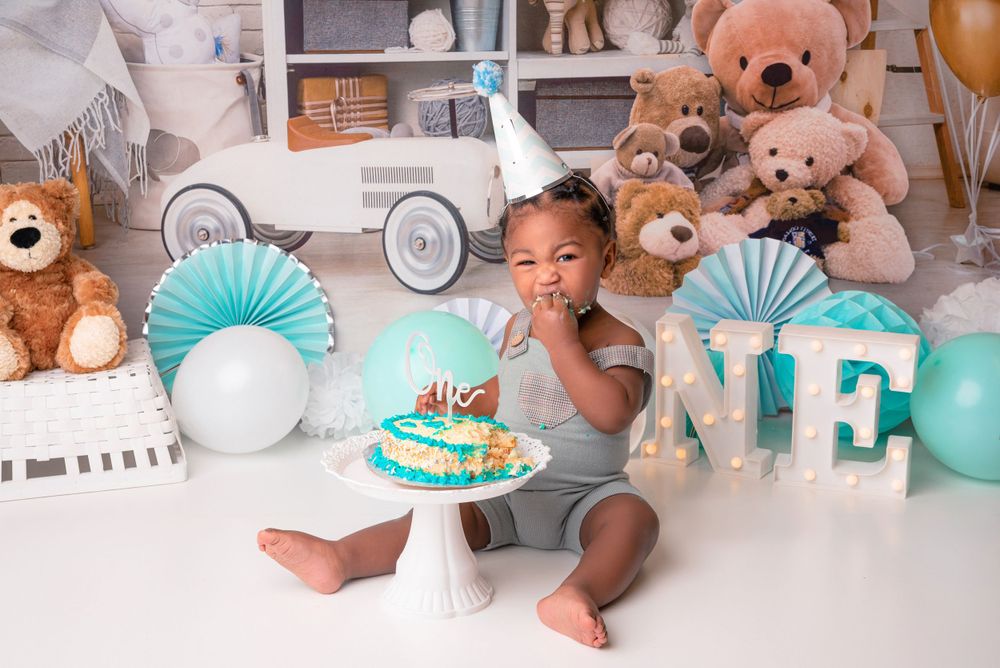 Baby in party hat surrounded by cake crumbs, laughing during cake smash Dudley