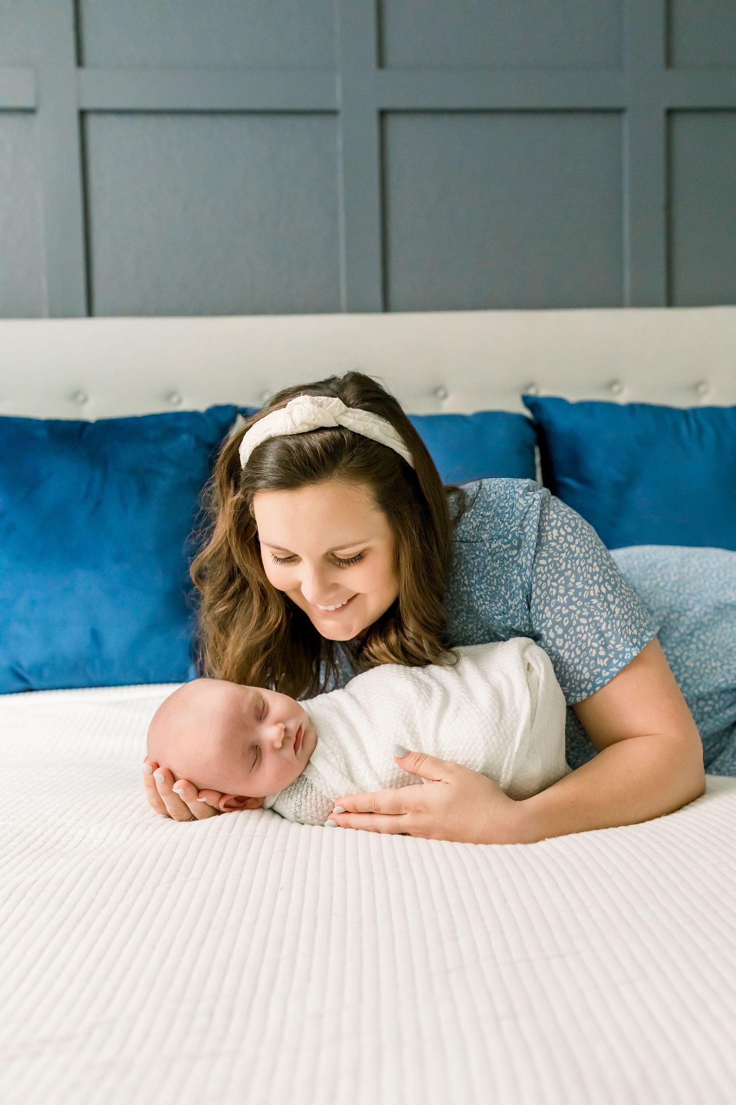 Tender moment captured on a comfortable bed with bright blue accent pillows.