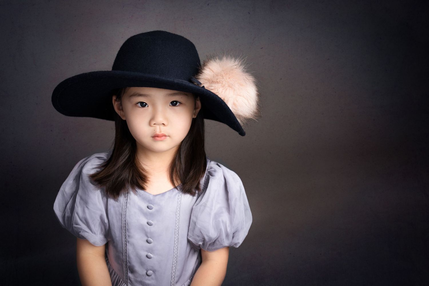 Portrait of someone in a black wide-brim hat with puff sleeves against a dark background.