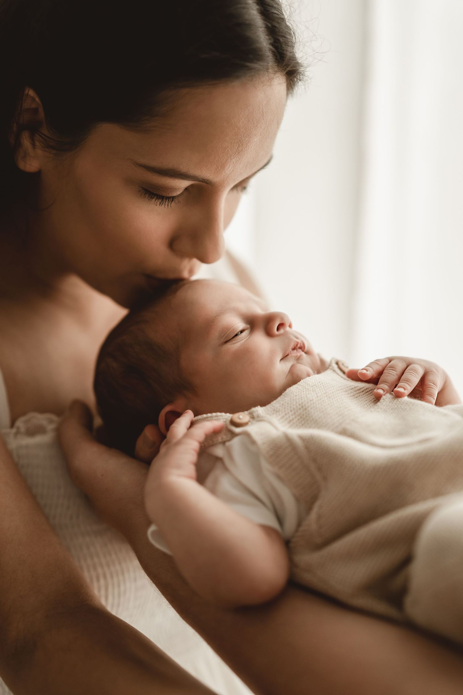 Intimate indoor portrait showing tender bonding moment in soft window light.