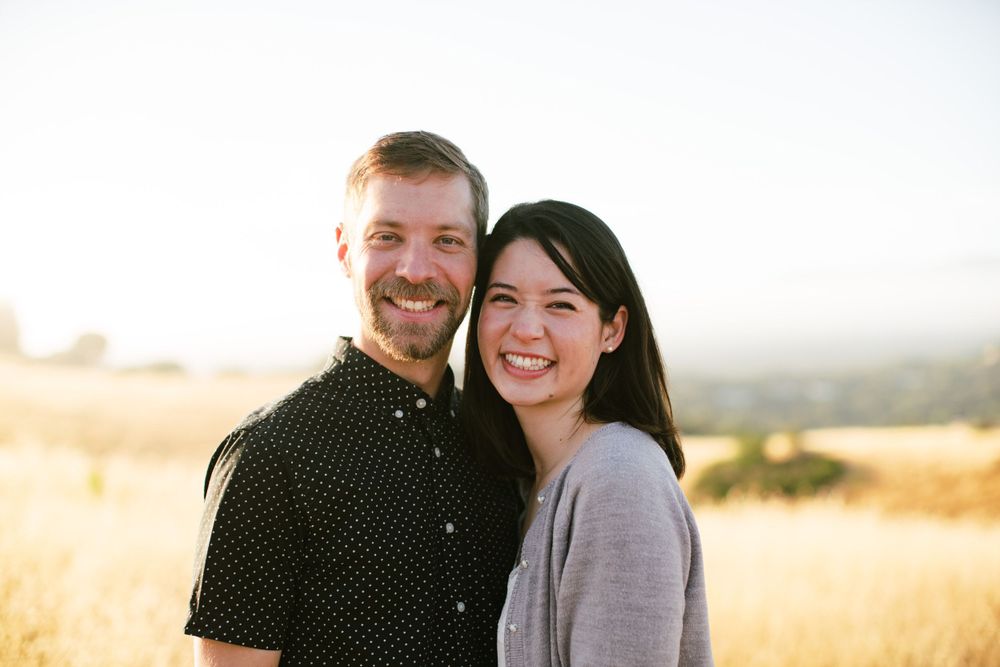 Happy couple smiling together in golden field during sunset.