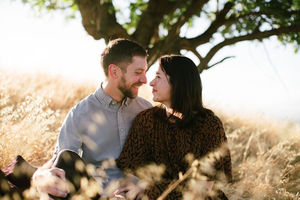 Intimate close-up of couple sharing tender moment under tree in golden light.
