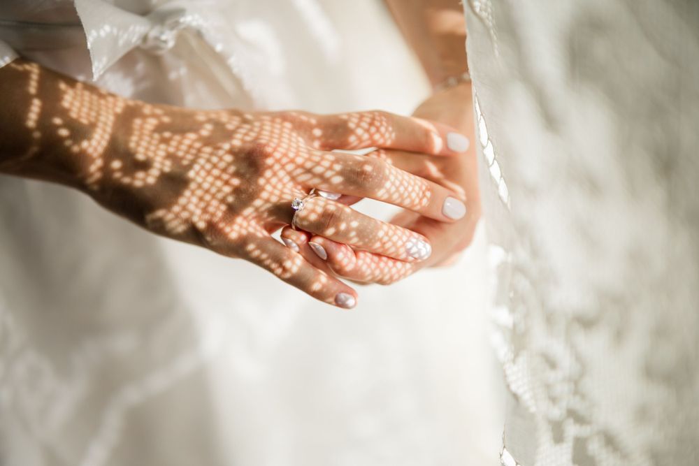 Close up of bride's hands with delicate lace detail on the window, capturing the beauty and elegance of the wedding day.
