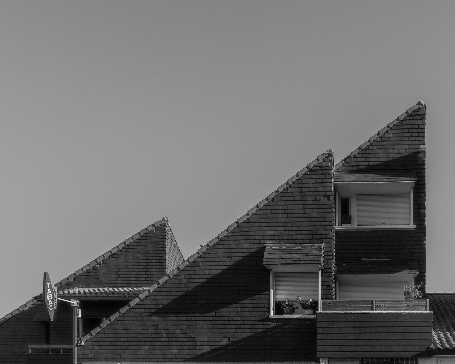 Abstract black and white architectural photograph of geometric building rooflines and shadows.