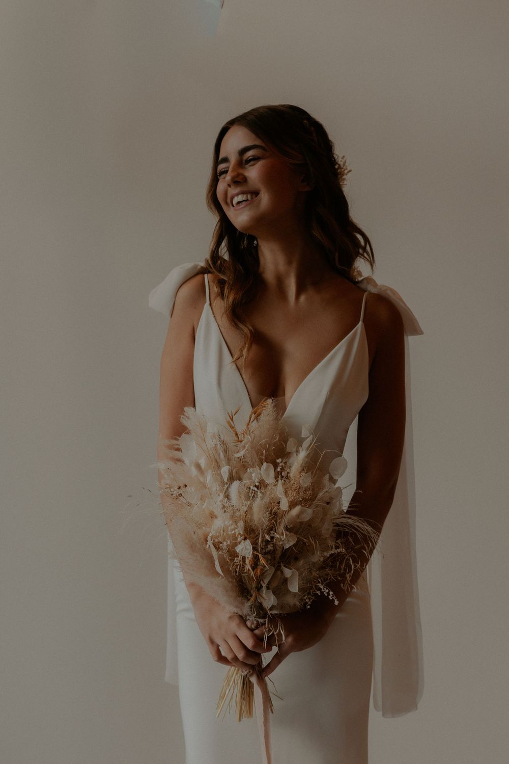 A radiant bridal portrait with a simple white dress and dried flower bouquet.