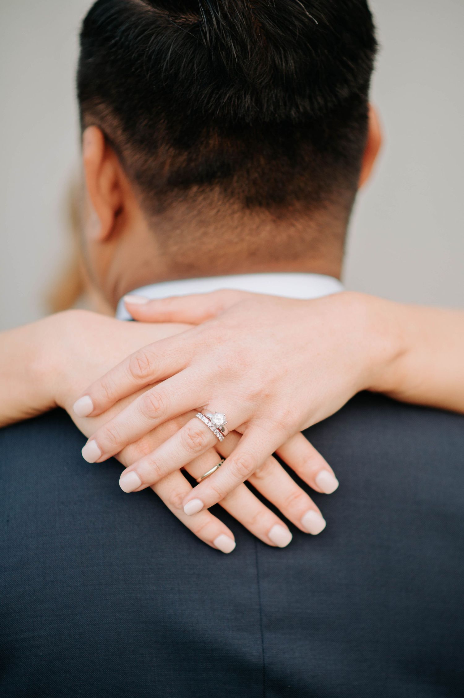 Close-up of embracing couple's hands showing off an engagement ring.