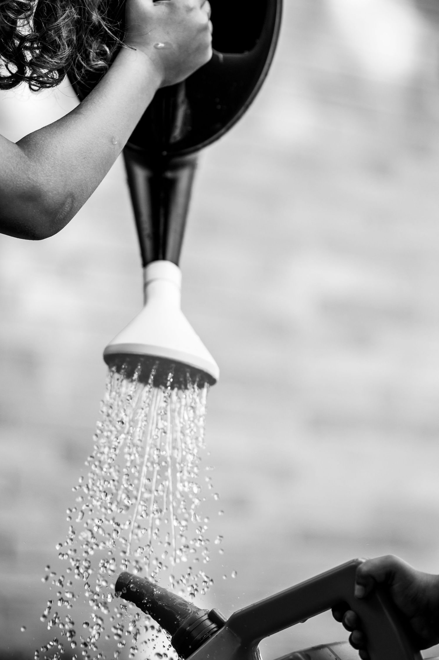 Black and white photo of water spraying from shower head.