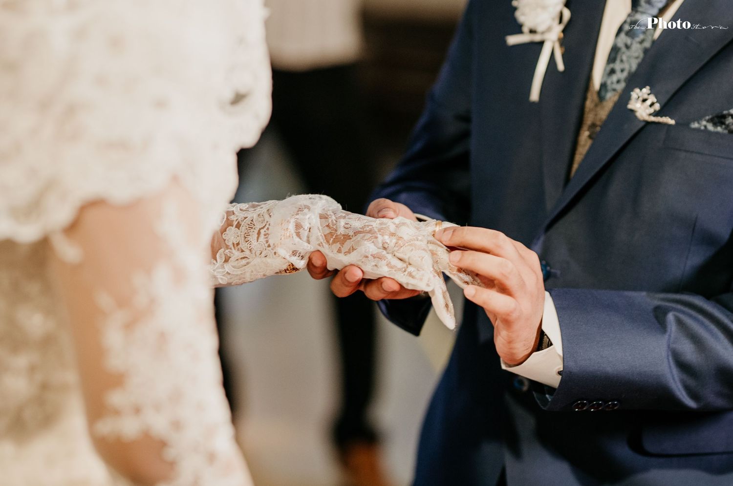 Close-up shot of hands during a wedding ceremony with elegant white lace details.