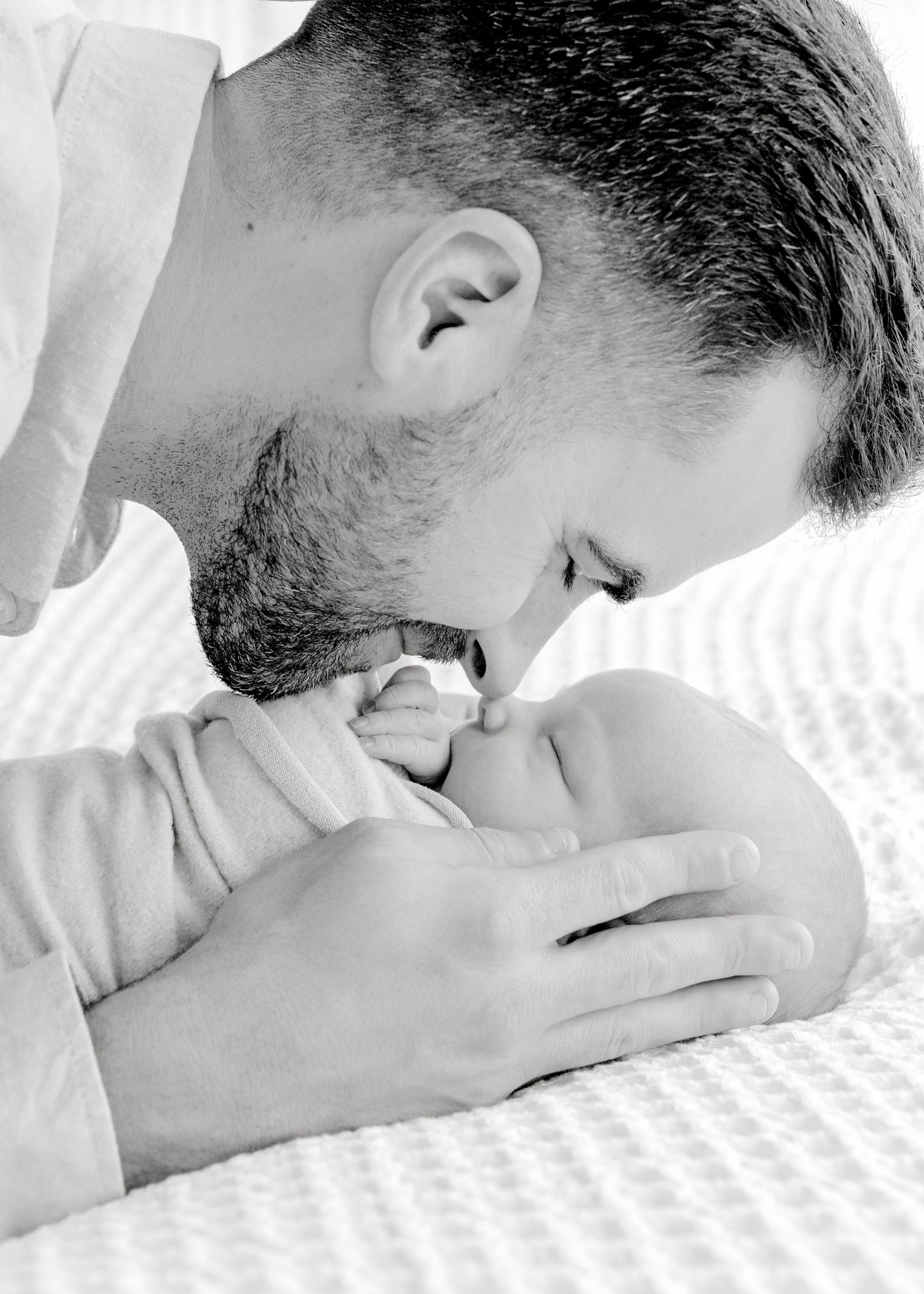 Intimate black and white portrait of someone nuzzling a newborn baby.