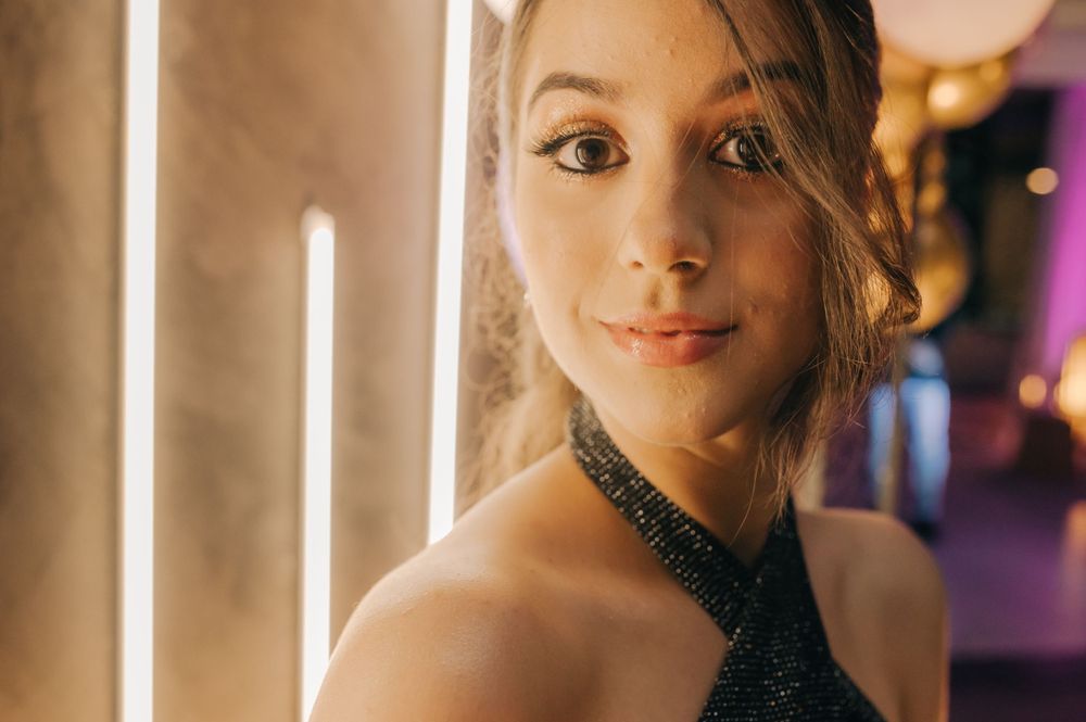 A close-up portrait with soft lighting and a glittering black halter neckline.