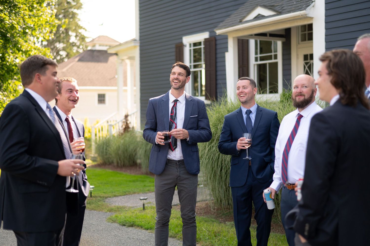 A group of well-dressed guests socialize during an outdoor gathering at a historic property.