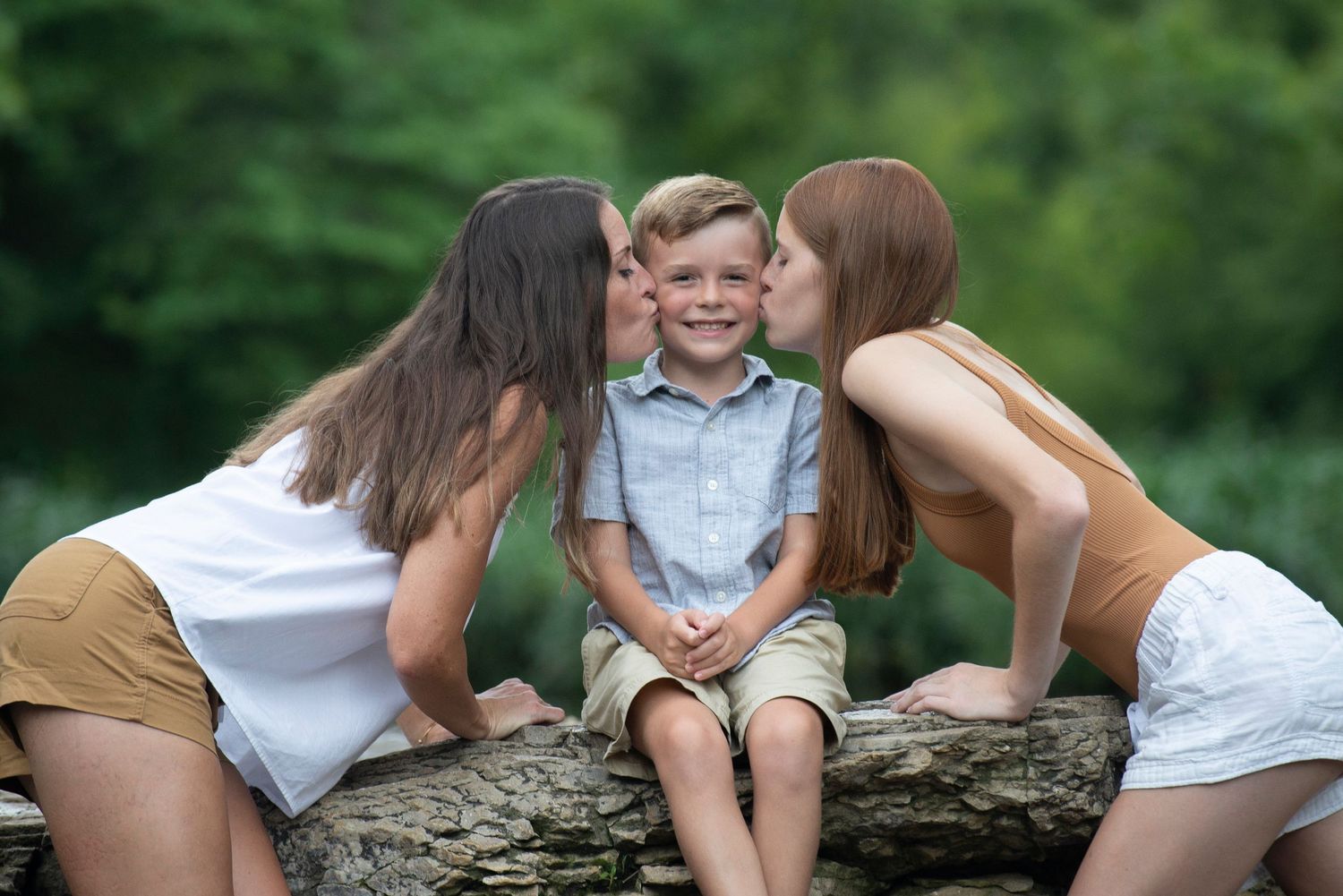woman and girl kissing each cheek of boy