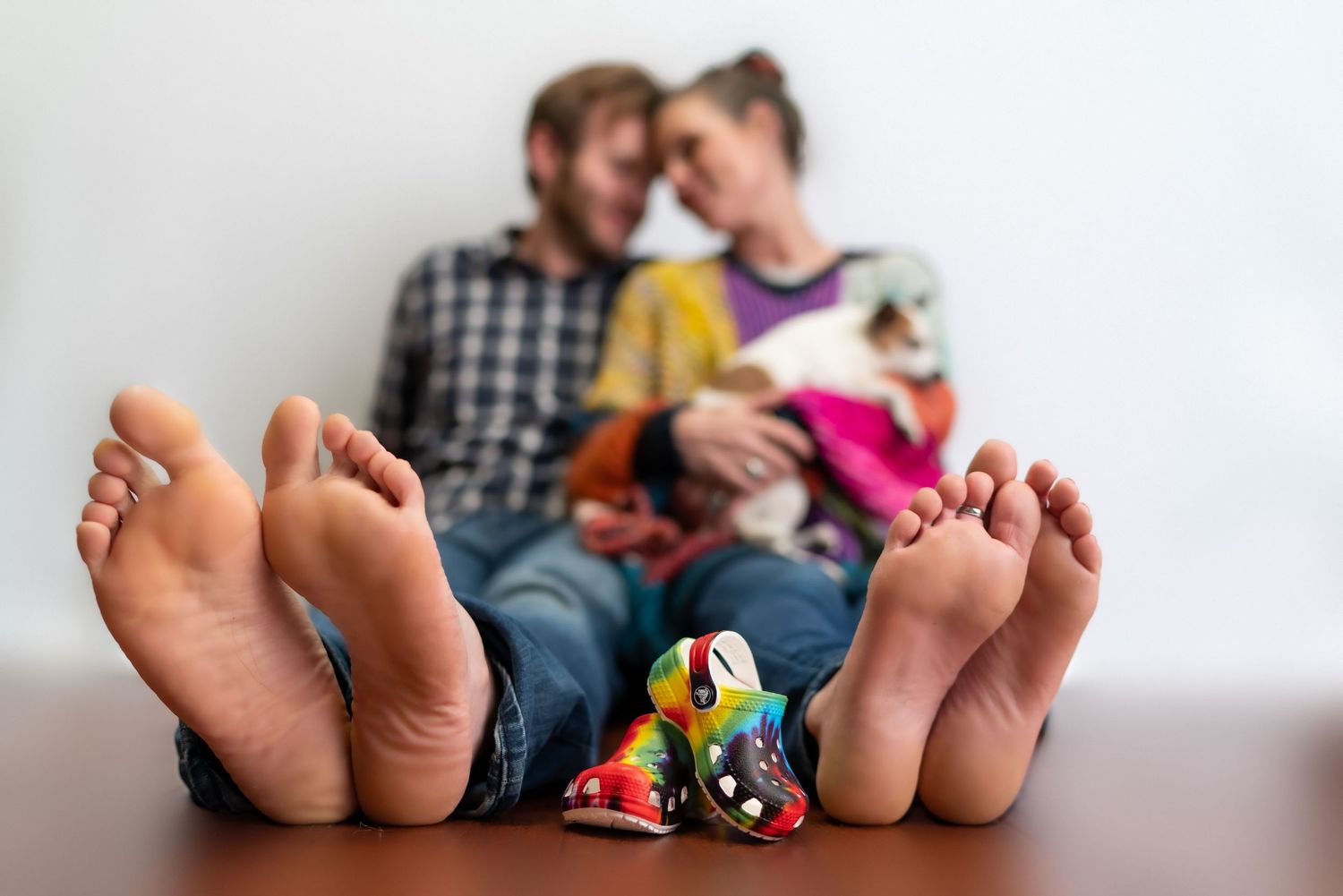 Family feet lined up on wooden floor with colorful toys.