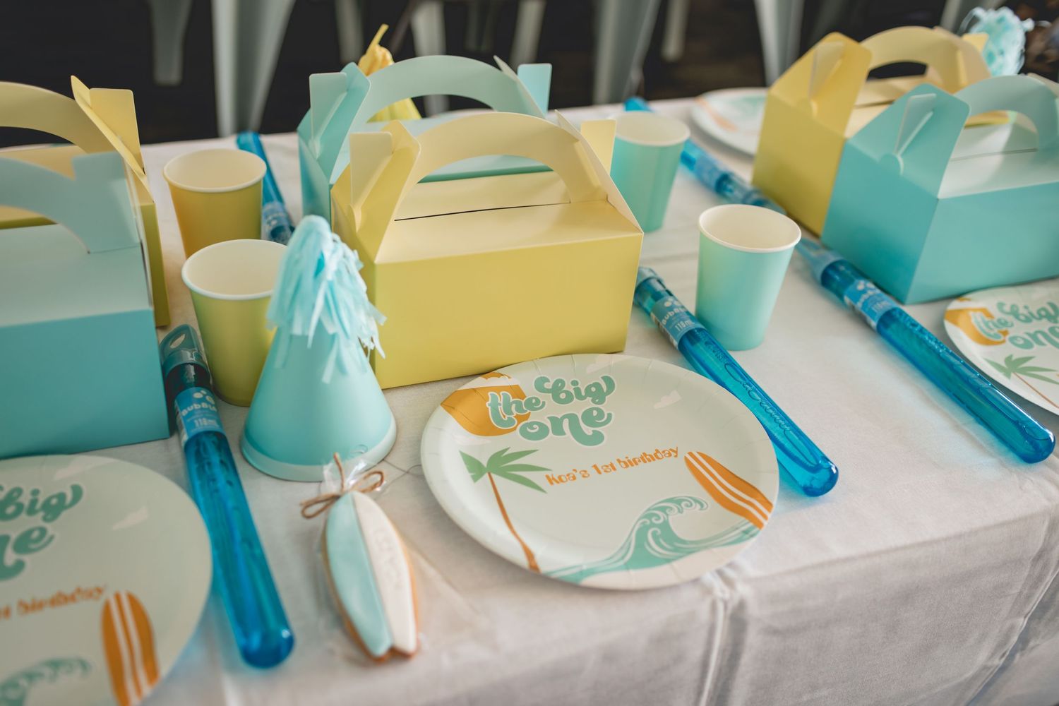 Party favor boxes in yellow and turquoise with matching plates and party decorations.