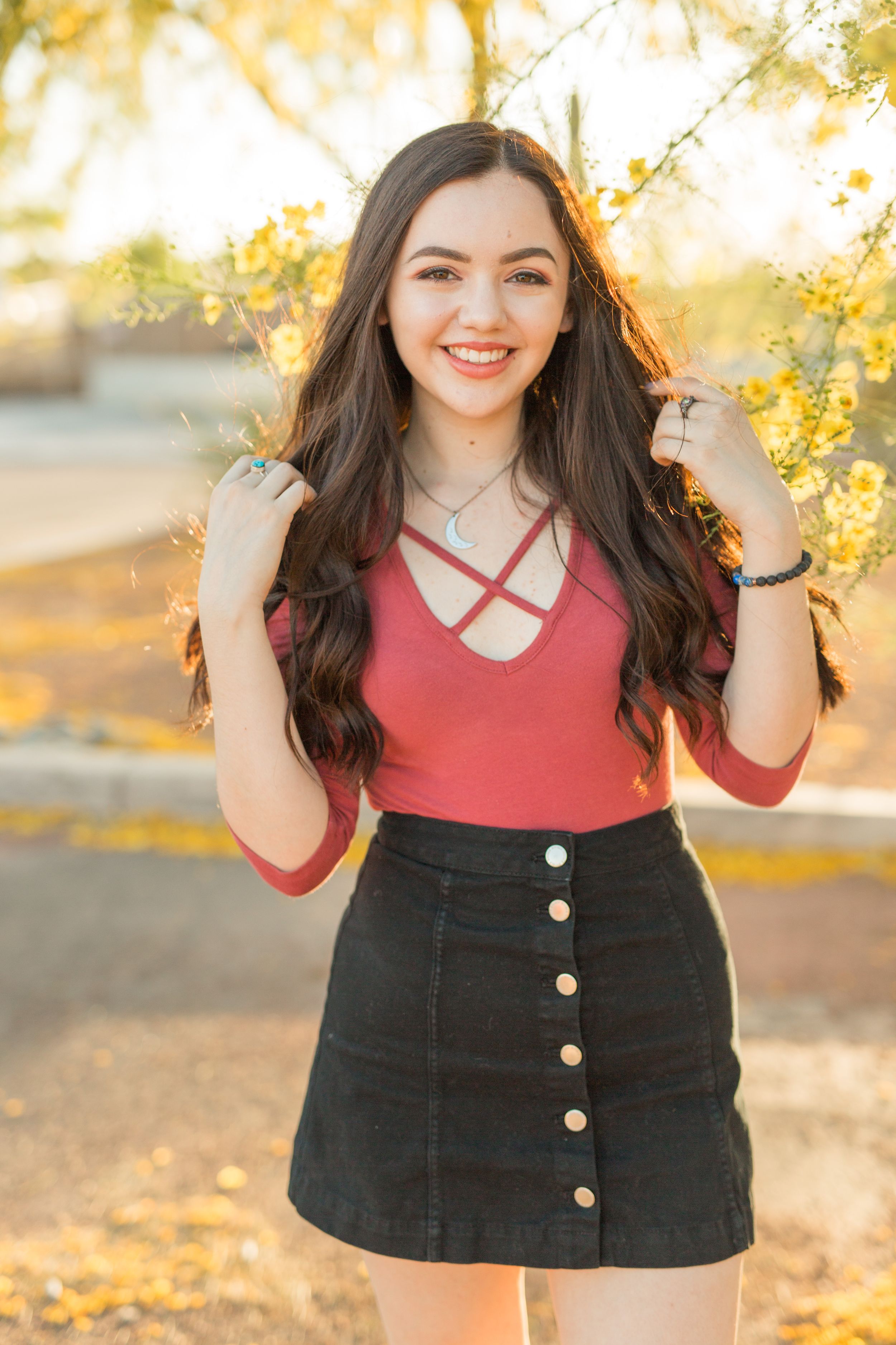 A stylish outfit featuring a coral top and button-front black skirt captured in golden sunlight.