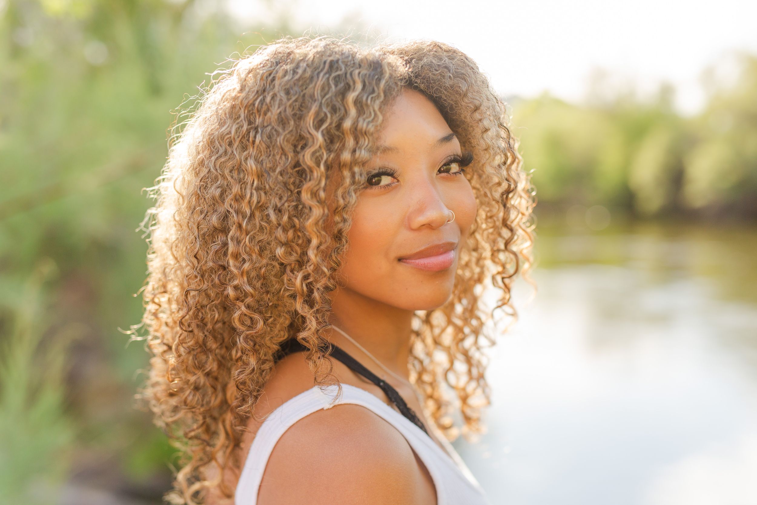 Natural curly hair portrait at sunset by water.