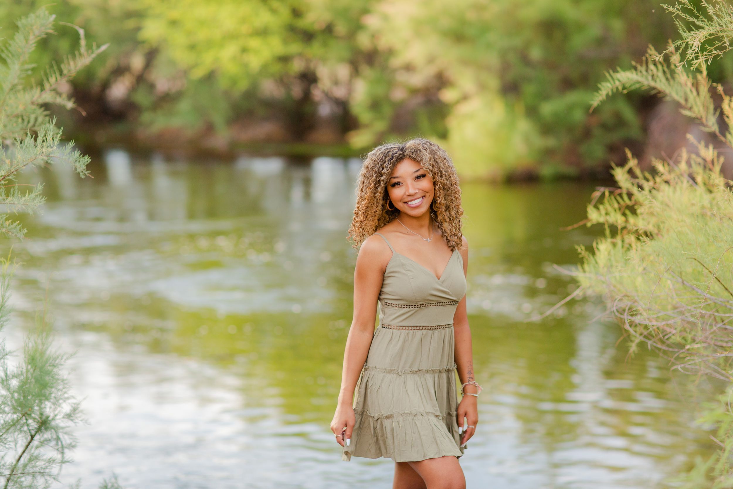 Summer portrait in beige dress by riverside with natural lighting.