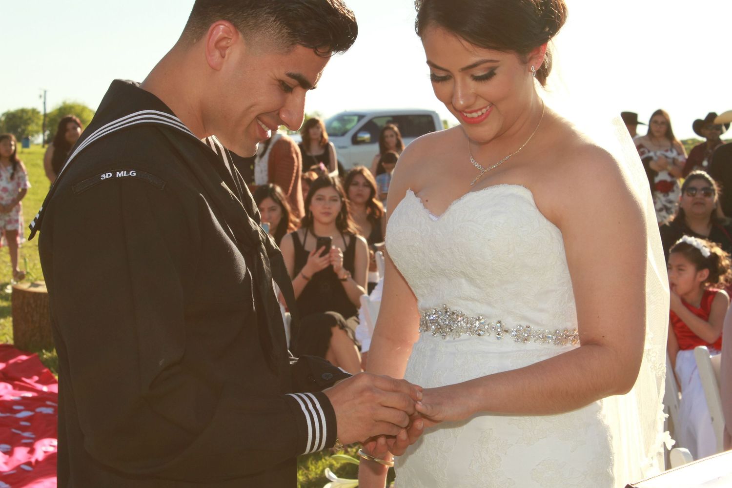 An emotional exchange of rings during an outdoor sunset wedding ceremony.