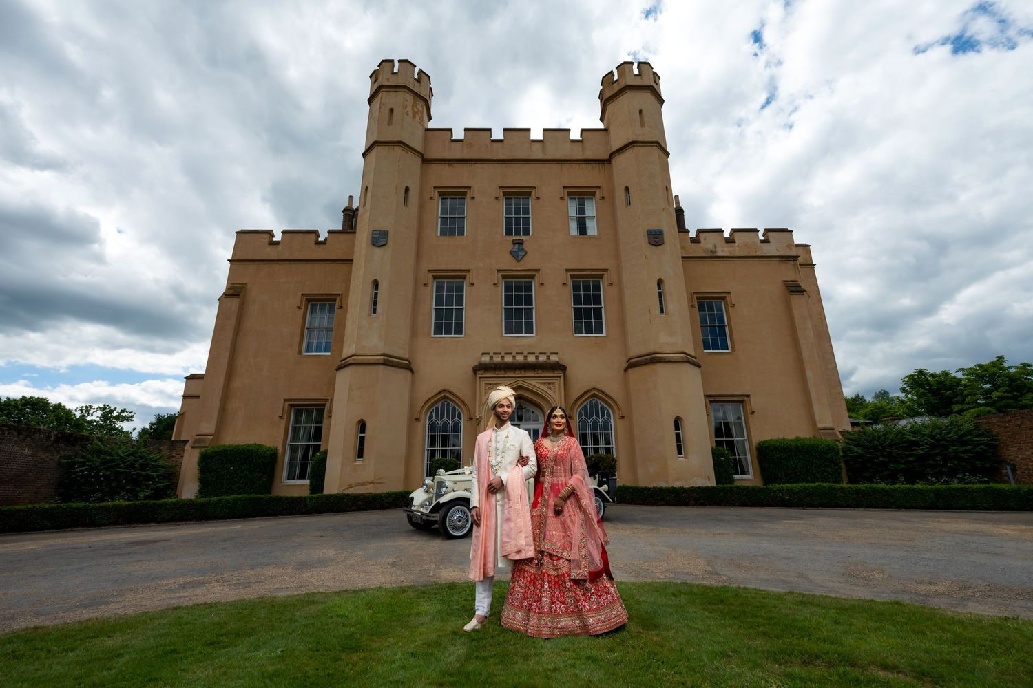 Wedding portraits in front of a majestic sand-colored castle with turrets.