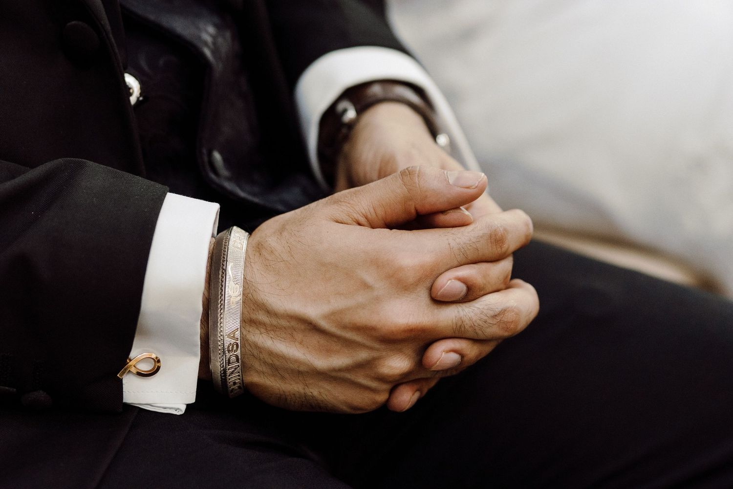 Detail shot of clasped hands during a formal wedding ceremony.