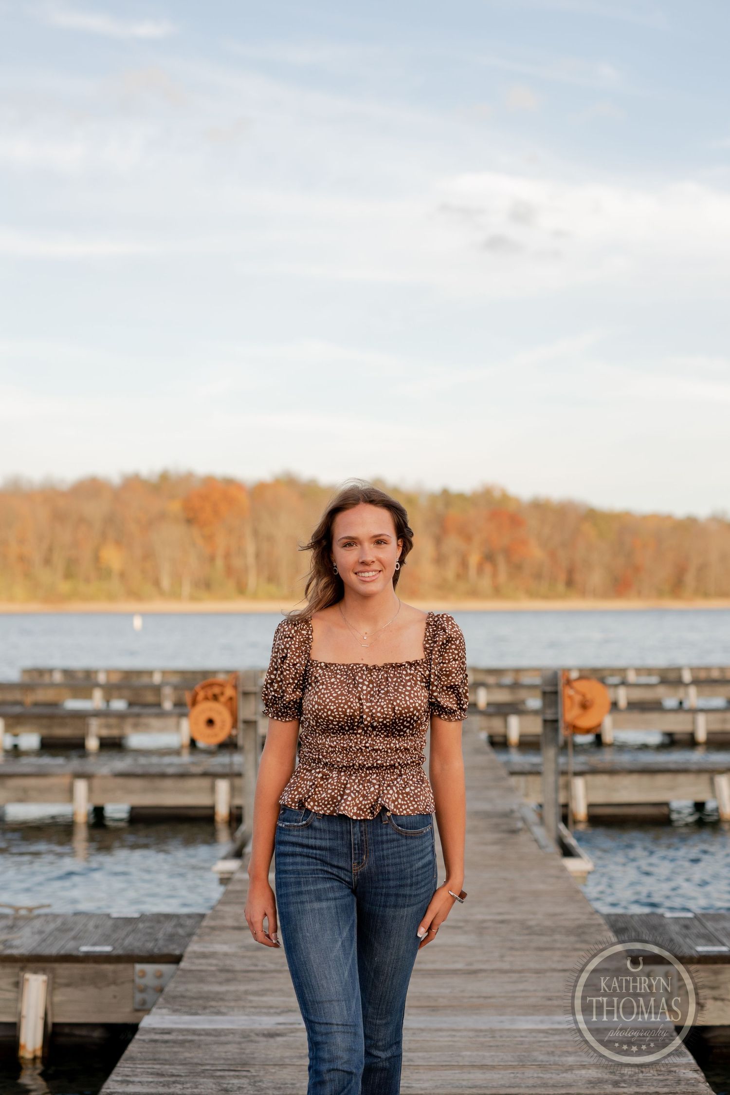 Casual outdoor portrait on a boat dock with fall colors and calm water in the background.