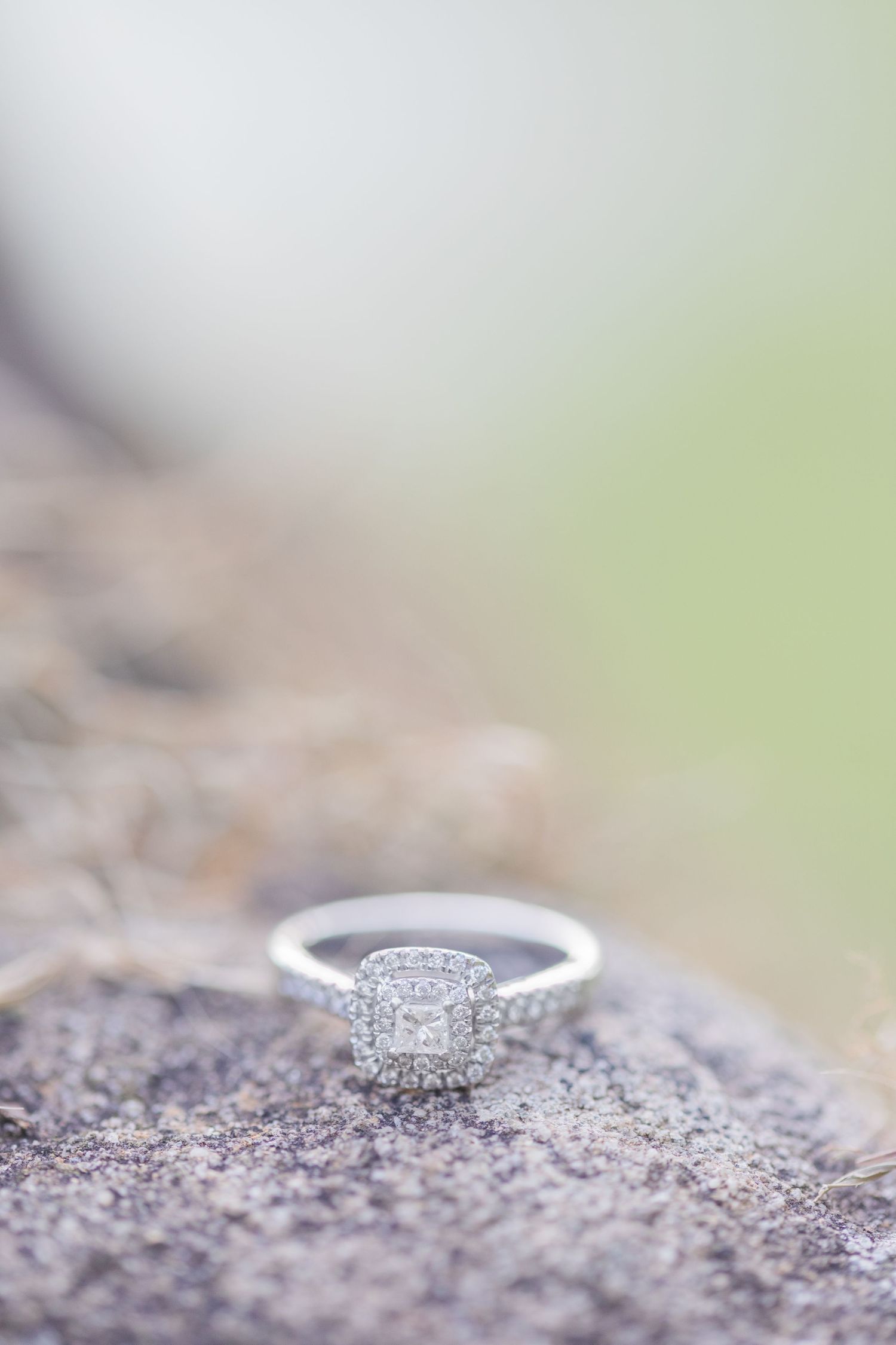 Elegant diamond engagement ring photographed with shallow depth of field on natural stone.