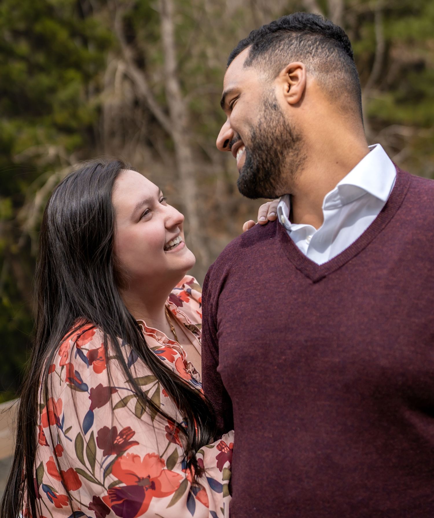 A couple sharing an intimate moment while surrounded by evergreen trees in a mountain setting.
