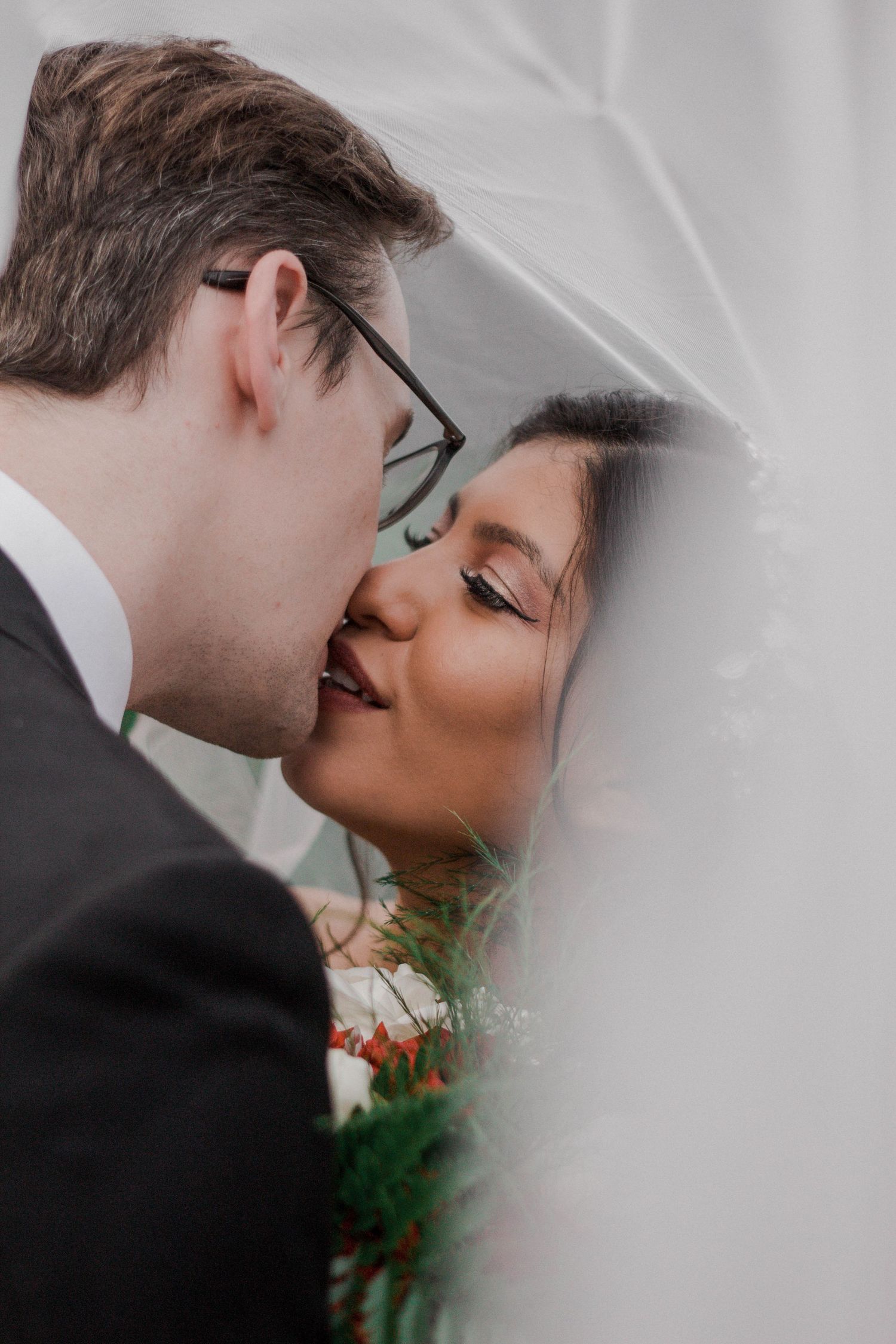 Romantic close-up of a couple kissing behind a delicate veil at their wedding ceremony. Wedding photographer Colorado