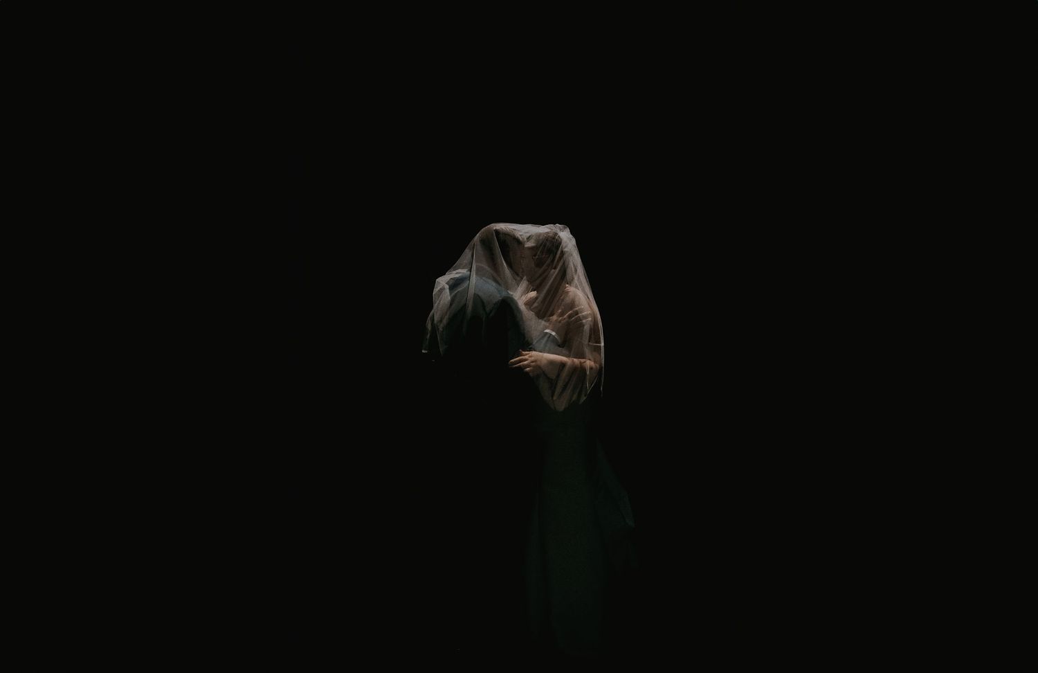 Silhouette of figure against dark background with dramatic lighting.