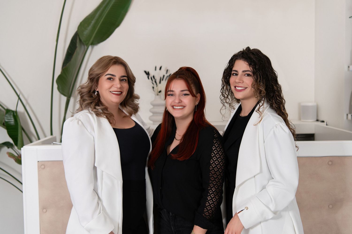 Group of women in white outfits laughing together in modern bright interior.