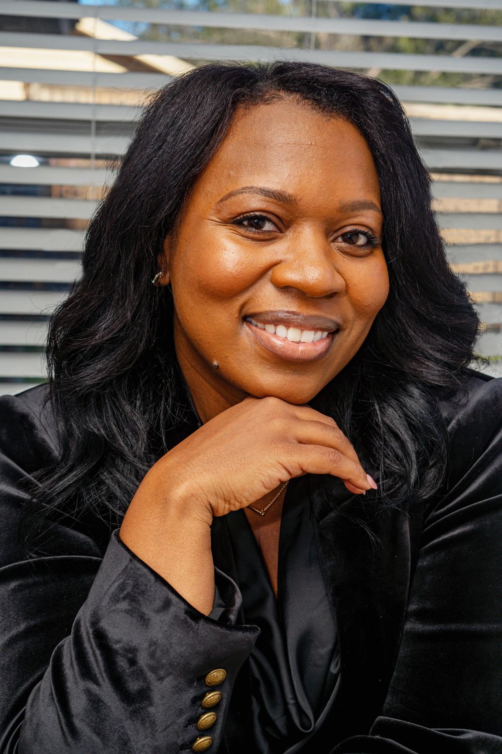 Close-up portrait of smiling woman in black velvet blazer indoors.