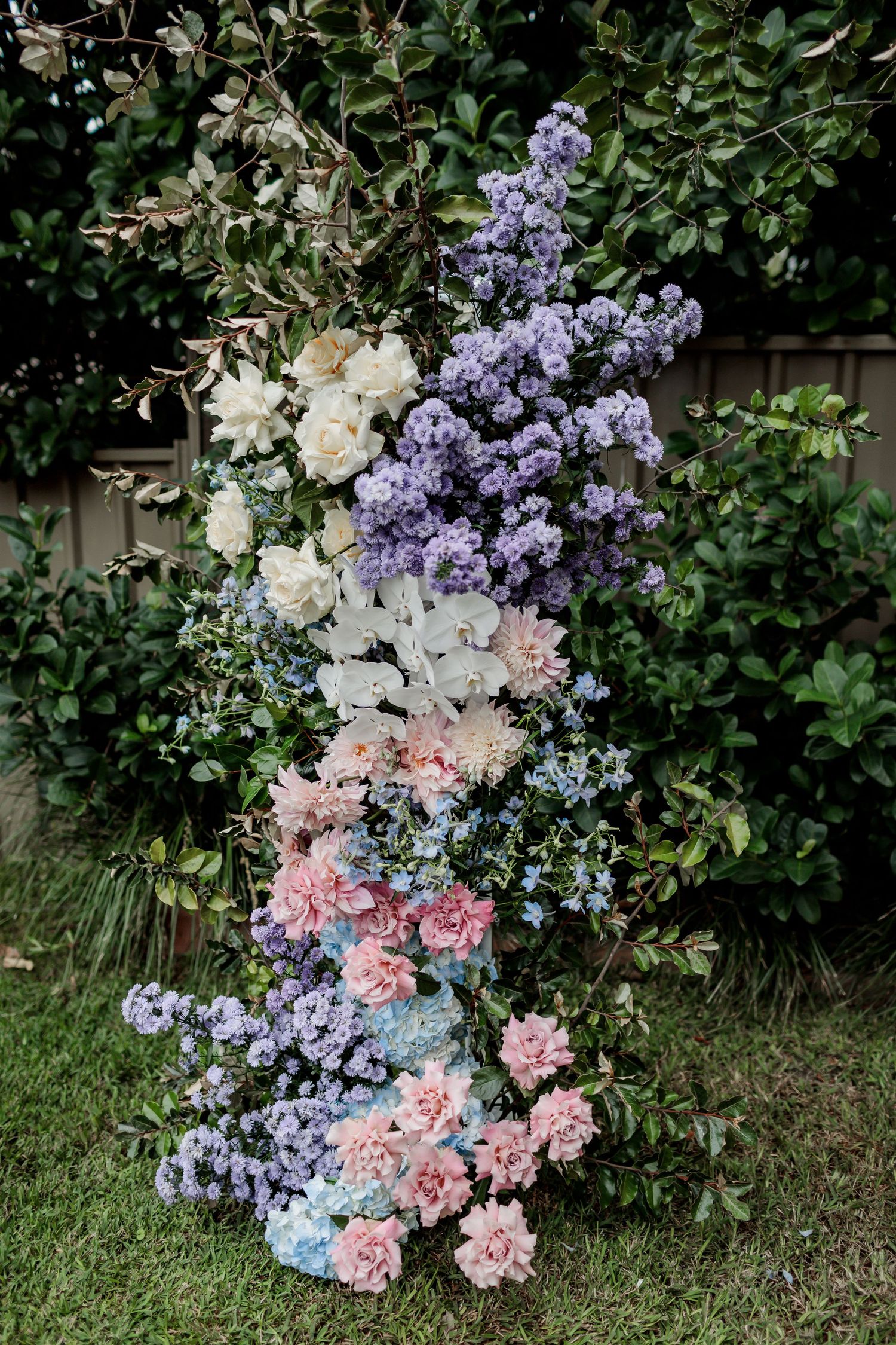 Beautiful floral arrangement with purple lilacs, white roses, and pink flowers against garden foliage.