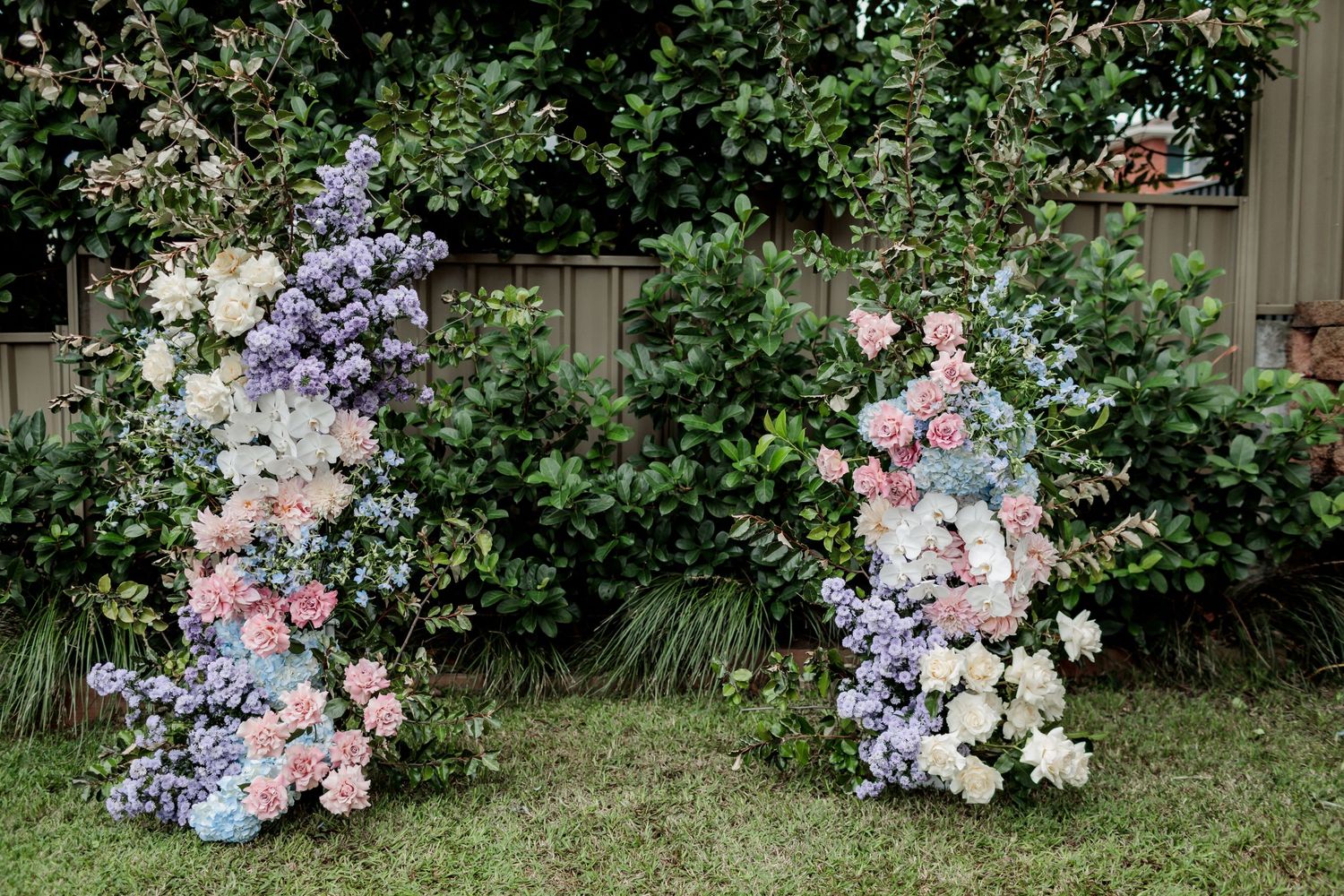 Two floral arches with pink, purple, and white flowers create an elegant garden display.