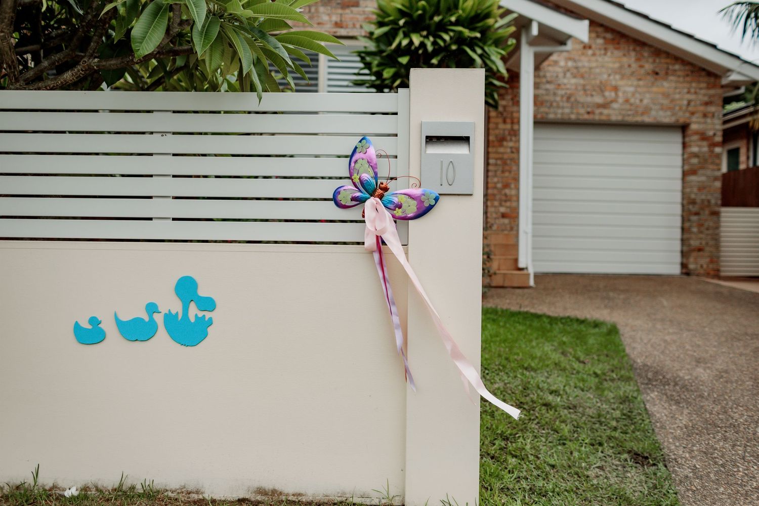 Decorative turquoise rubber ducks line up along a white fence with floral ribbons.