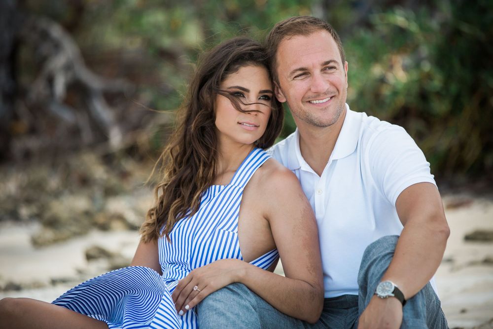 couple sitting on the sand looking in the ocean during an engagement session at Virginia key park in Key Biscayne