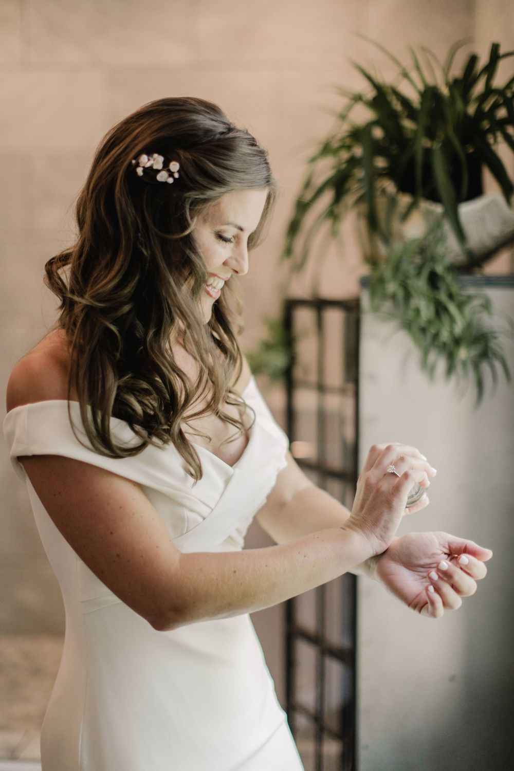 An elegant off-shoulder wedding dress with delicate hair accessories in a natural indoor setting.